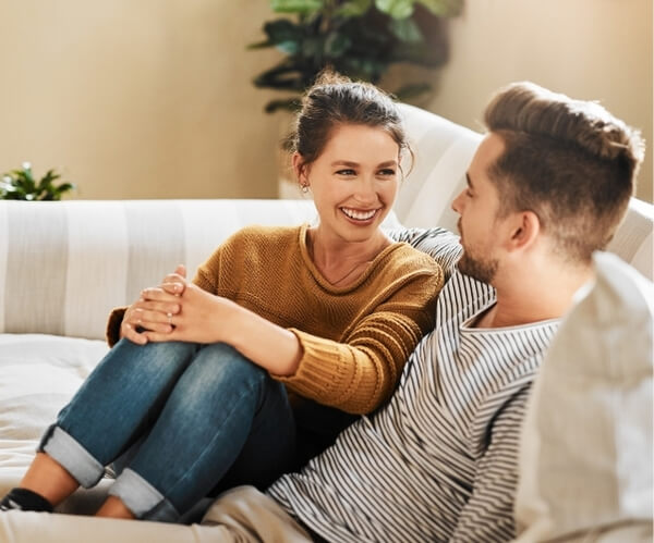 Inteligencja emocjonalna w relacjach – klucz do głębszego porozumienia. Para siedzi na kanapie, uśmiechają się do siebie, są w porozumieniu.